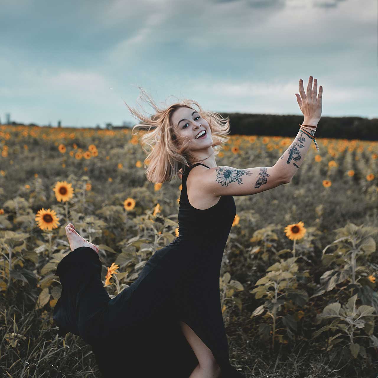 Photo of a happy woman jumping through a field of sunflowers