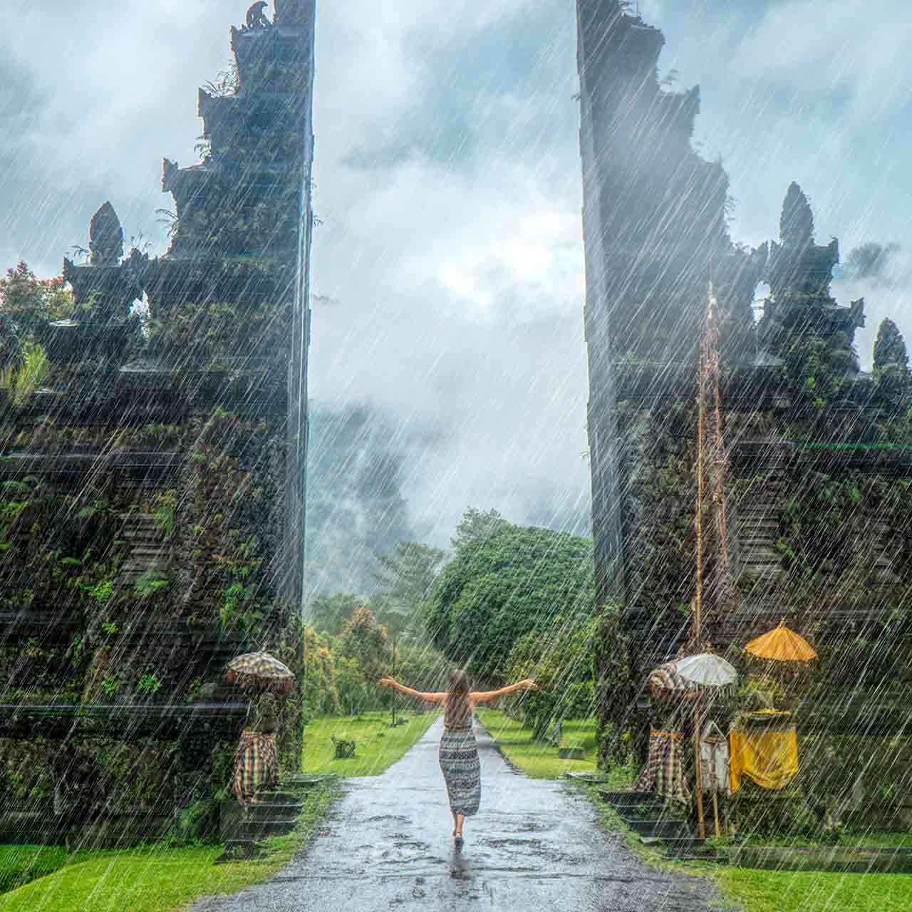 Photo of a woman standing in an Asian temple during rain