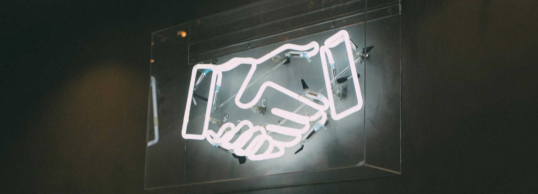 Neon sign of shaking hands symbolizing affiliate partnership