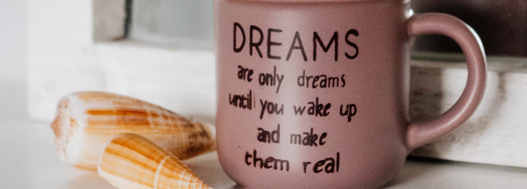 Photo of a coffee mug that has an inspirational quote on it, sayin Dreams are only dreams until you wake up and make them real